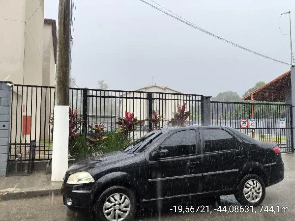 Apartamento preto com portão metálico ao fundo em área residencial nublada