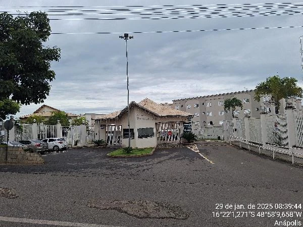 Apartamento branco em condomínio com guarita e portão de entrada em área asfaltada e arborizada