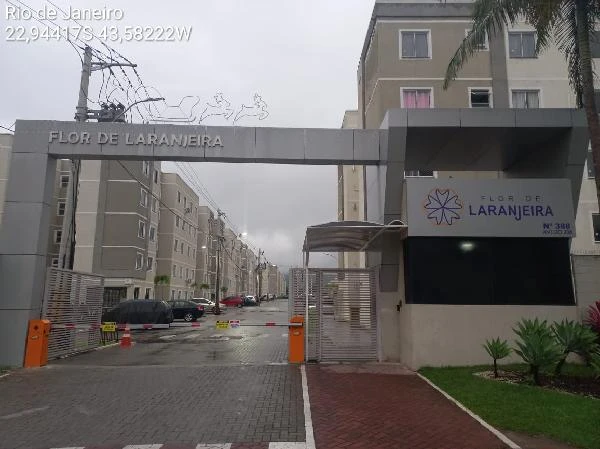 Apartamento com fachada cinza no condomínio Flor de Laranjeira com entrada principal e guarita