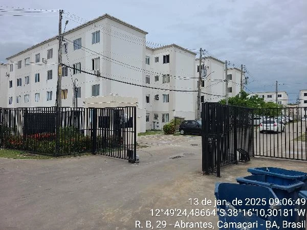 Apartamento branco em condomínio com portão de ferro preto e estacionamento em área externa