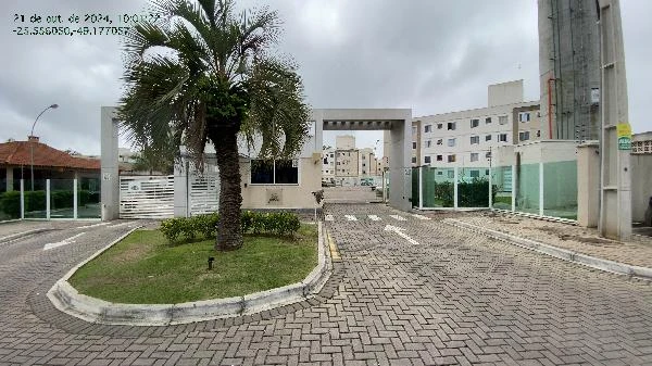 Apartamento branco em condomínio com portaria e área verde na entrada em dia nublado