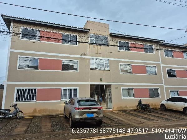 Apartamento bege de 44m² com 2 andares em condomínio residencial, fachada simples e área de estacionamento com veículos