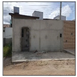 Casa cinza em construção com fachada sem acabamento em área residencial com terreno frontal