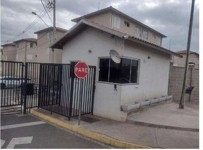 Apartamento branco de 47 metros quadrados no 1º pavimento com janela e grade de segurança em condomínio residencial com guarita e placa de pare