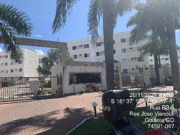Apartamento branco em condomínio fechado com portaria, calçada com palmeiras e áreas verdes bem cuidadas