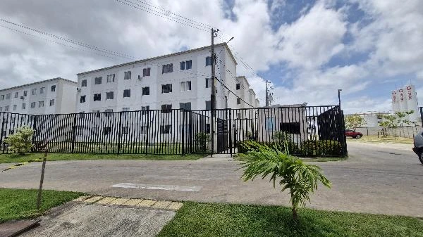 Apartamento branco de 4 andares com grades pretas e áreas verdes em condomínio fechado