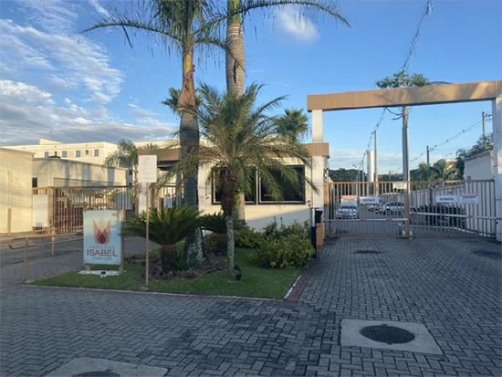 Entrada de condomínio residencial com guarita, portão eletrônico, calçamento e palmeiras ao redor