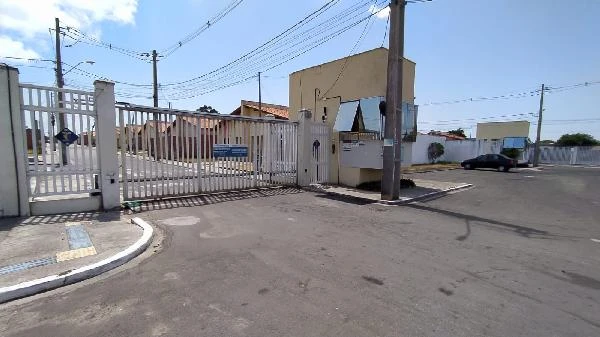 Casa com portão branco e guarita em condomínio residencial sob céu claro