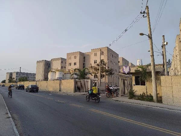 Apartamento bege no condomínio residencial com quatro andares e portaria na rua asfaltada