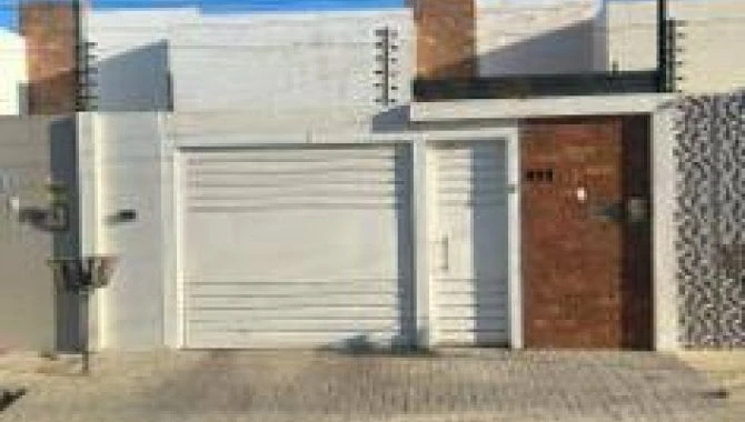 Casa padrão com fachada branca, portão de garagem e porta de entrada de madeira em área urbana pavimentada