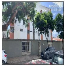 Apartamento com fachada de prédio baixo em área urbana com algumas árvores e carros estacionados na rua
