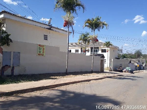 Apartamento branco com muro alto em condomínio residencial, vista da rua com calçamento e árvores próximas