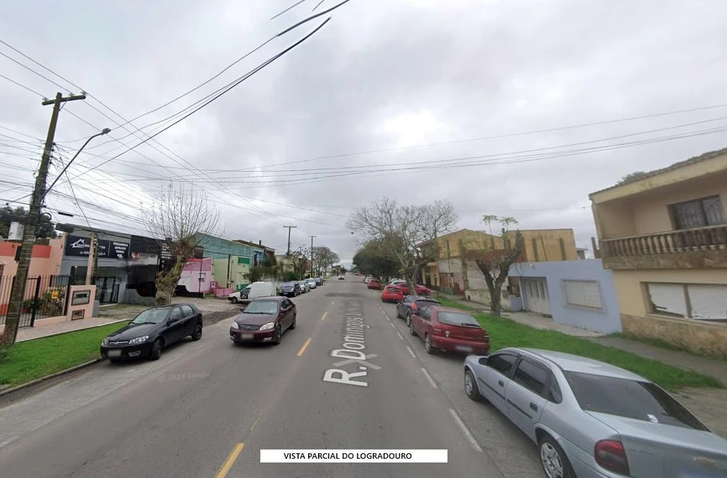 Casa residencial com fachada simples clara e varanda na Cidade Nova vista da rua com carros estacionados e calçada gramada