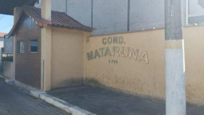 Casa em condomínio com muro amarelo e portão ao lado de rua pavimentada fachada simples