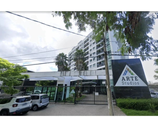 Apartamento branco no Condomínio Arte Studios com guarita e área externa com carros estacionados