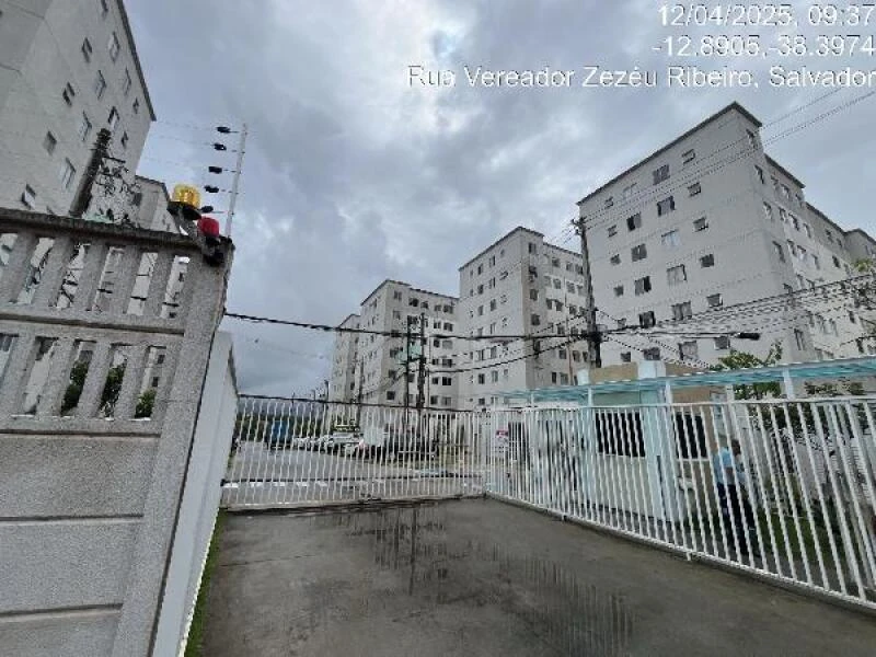 Apartamento branco em condomínio residencial com portaria e vários prédios ao redor em área urbana