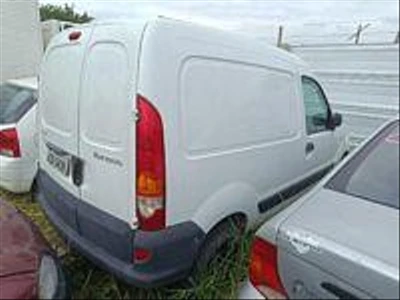 Automóvel branco Renault Kangoo Express 2014 com carroceria fechada estacionado entre veículos em área externa com sinais de abandono
