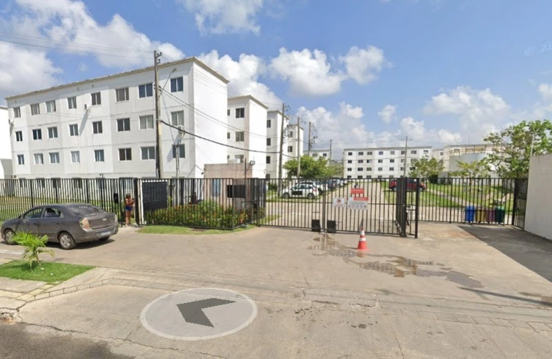 Apartamento branco com vários blocos em condomínio residencial com portão de entrada e área de estacionamento