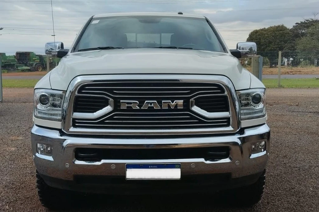 Automóvel branco Dodge Ram Laramie 2018 com grade frontal cromada em área externa com piso de cascalho