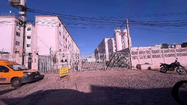 Apartamento rosa no Condomínio Residencial Recanto da Maraponga com portão metálico e calçada em paralelepípedo