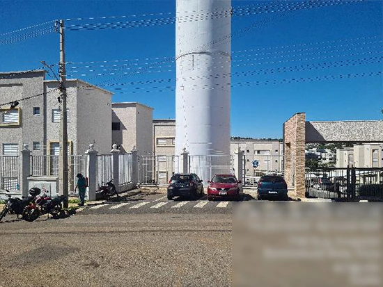 Apartamento bege em condomínio fechado com portão de entrada e três carros estacionados na frente