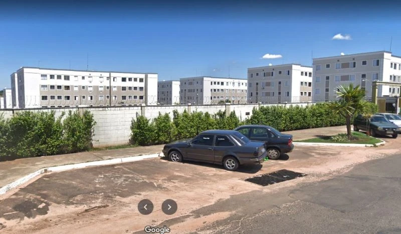 Apartamento branco de 4 andares em condomínio residencial com área externa e estacionamento aberto
