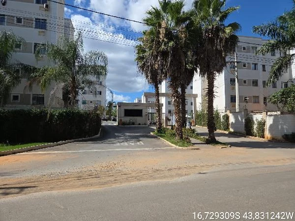 Apartamento branco em condomínio residencial com portaria e área externa arborizada vistas ao dia ensolarado