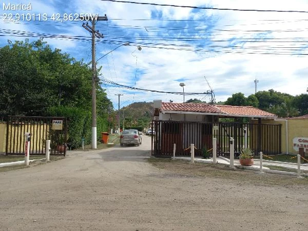 Casa branca com telhado vermelho no condomínio Fazendinha do Retiro com portaria e área externa