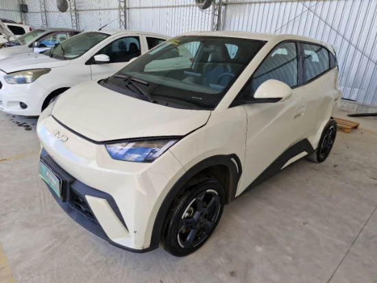 Automóvel branco Byd Dolphin Mini GS5EV 2024 2025 elétrico 4 portas estacionado em galpão com leve amassado na lateral
